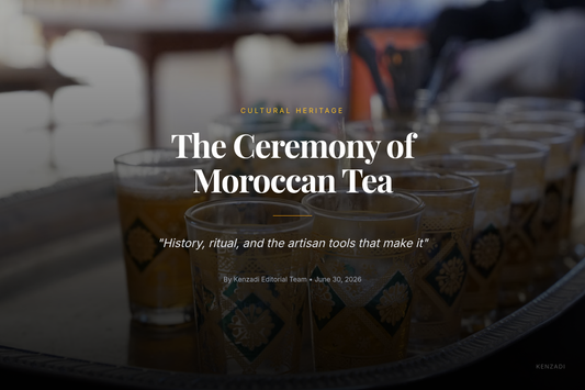 A person's hands pouring Moroccan mint tea from a traditional brass teapot into a small glass from a